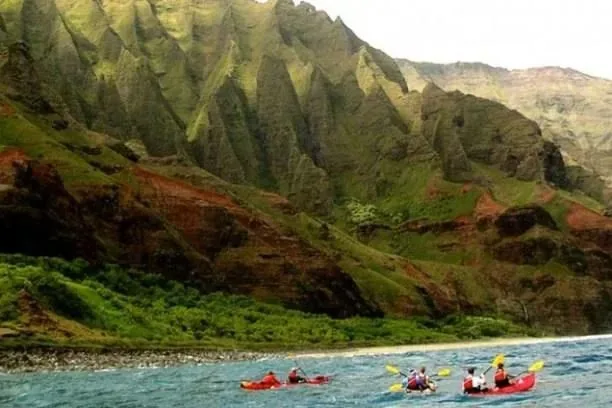 Kayakers beneath the fluted green cliffs of the Na Pali Coast